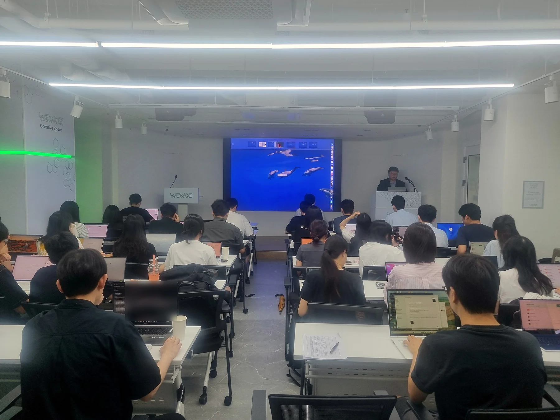 1인 1노트북으로 AI 에이전트 실습에 참여한 강의실 전경, 강단에 선 이강준 강사